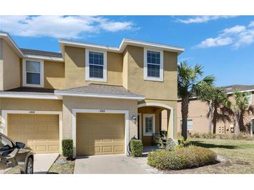 Inviting exterior of a two-story townhome featuring a private garage, lush landscaping and a sunny sky at 6907 Holly Heath Dr, Riverview, FL 33578