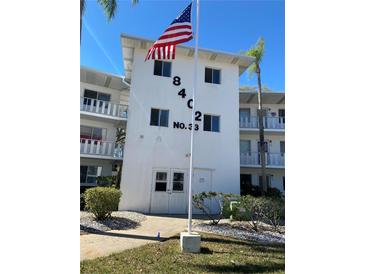 Condominium building exterior with an American flag, lush landscaping and impact windows at 8402 111Th St # 303, Seminole, FL 33772