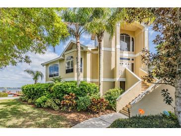 Beautiful two-story tan home with lush landscaping and a view of the water at 104 Westbrook Ct, Safety Harbor, FL 34695