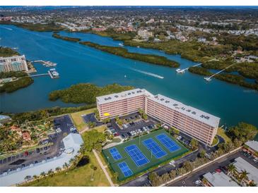 Beautiful aerial view of a large condo building near a bay and tennis courts on a sunny day at 19451 Gulf Blvd # 301, Indian Shores, FL 33785