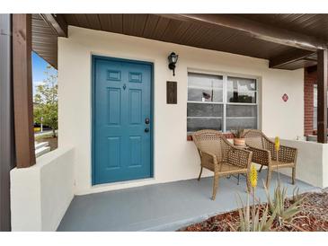 Charming front porch featuring a vibrant blue door, seating, and manicured landscaping at 24862 Us Highway 19 N # 1701, Clearwater, FL 33763