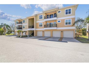 Spacious condo building featuring balconies, individual garages, and lush landscaping at 5088 Royal Palms Way # 304, New Port Richey, FL 34652