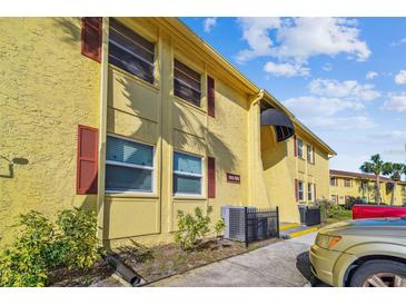 Condo with yellow siding, dark red shutters, and a well-kept lawn on a sunny day at 7512 Dolonita Dr # 7512, Tampa, FL 33615