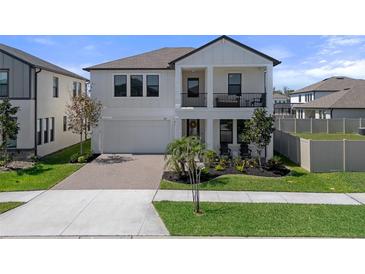 Beautiful two-story home featuring a balcony, a well-manicured lawn, and a brick driveway at 9817 Coneflower Ct, Land O Lakes, FL 34637