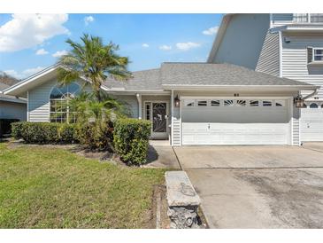 Charming single-story home featuring a two-car garage, lush landscaping, and mature palm trees at 11722 Currie Ln # B3, Largo, FL 33774