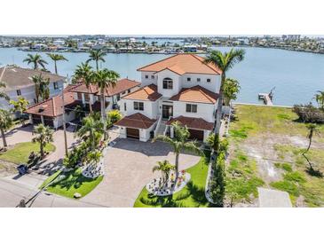 Waterfront home with lush landscaping, a tile roof, and large driveway provides curb appeal at 16327 Redington Dr, Redington Beach, FL 33708