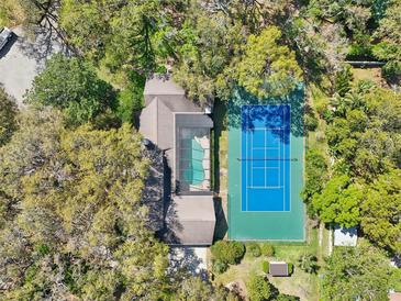 Aerial view of a luxurious home with a pool and tennis court surrounded by lush greenery at 2112 Laurence Dr, Clearwater, FL 33764