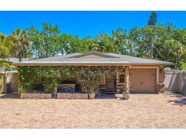 Charming single-story home featuring a brick driveway, lush greenery, and a cozy front porch at 2121 Park N St, St Petersburg, FL 33710