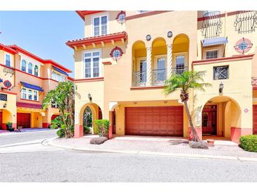 Mediterranean-style home with a two-car garage, arched entryway, balconies, and lush landscaping at 250 Seagate Ct, Dunedin, FL 34698