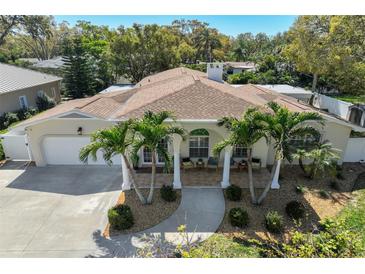 Beautiful home featuring a well-manicured lawn, mature palm trees, and a charming front porch at 609 Osceola Rd, Belleair, FL 33756