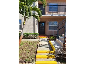 Inviting front entrance with a walkway and stairs leading to the unit's door, enhanced by a mature palm tree at 1010 Bowsprit Ln # 0, Holiday, FL 34691