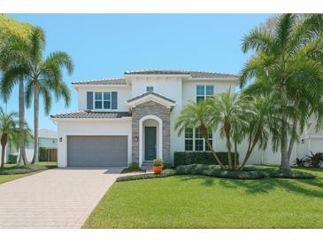 Beautiful two-story home featuring tropical landscaping, a stone entrance, and a gray garage door at 4612 W Lowell Ave, Tampa, FL 33629