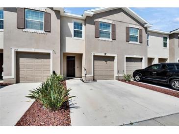 Beige two-story townhouse featuring a one car garage, front door, rock landscaping and a well maintained lawn at 708 Barclay Wood Dr, Ruskin, FL 33570