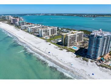 Stunning aerial view of beachfront condos along a sandy beach with blue ocean waters on a sunny day at 1480 Gulf Blvd # 401, Clearwater Beach, FL 33767