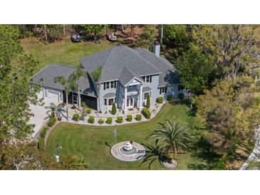 Stunning aerial view of a beautiful two-story home, showcasing its manicured lawn, fountain, and lush surroundings at 27625 Lincoln Pl, Wesley Chapel, FL 33544