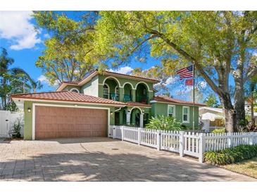 Charming two-story home boasts mature trees, a two-car garage, a quaint white picket fence, and an American flag at 550 7Th S St, Safety Harbor, FL 34695
