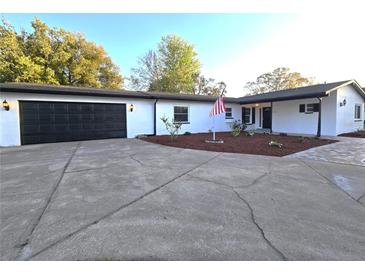 Charming single-story home features an attached two-car garage, a manicured lawn and an American flag at 9308 Pinero St, Spring Hill, FL 34608