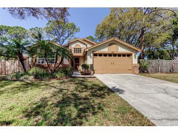 Charming single-story home with a well-manicured lawn, mature trees, and a two-car garage at 592 Deer W Run, Palm Harbor, FL 34684