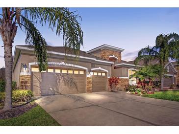 Charming home featuring a three-car garage, stone accents, manicured landscaping, and a well-maintained lawn at 31707 Holcomb Pass, Wesley Chapel, FL 33543