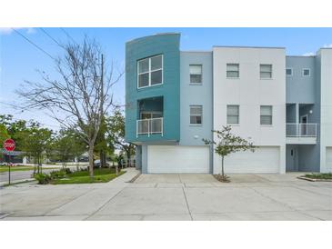 Modern townhome with a light teal and white exterior, featuring a two-car garage and manicured landscaping at 3405 W Swann Ave # 9, Tampa, FL 33609