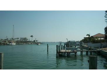Scenic waterfront view featuring calm water, docks, and tropical trees under a clear sky at 390 Belle Point Dr, St Pete Beach, FL 33706