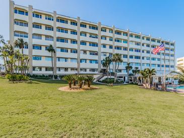Stunning multi-story building with a well-manicured lawn, palm trees, and an American flag waving proudly at 100 Bluff View Dr # 317A, Belleair Bluffs, FL 33770