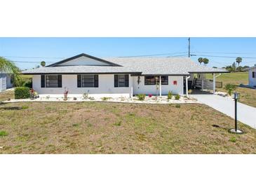 Charming single-story home with a well-manicured lawn and a driveway leading to a covered carport at 1021 Augusta Dr, Sun City Center, FL 33573
