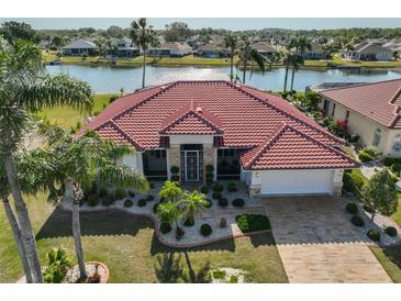 Beautiful single-story home features a red tile roof, lush landscaping, and a paver driveway at 1123 Signature Dr, Sun City Center, FL 33573