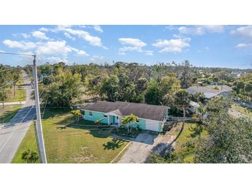 Charming one-story home with light blue exterior, green grass and palm trees at 311 Ravenna N St, Nokomis, FL 34275