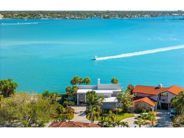 Waterfront home with a private drive surrounded by lush landscaping, palm trees, and stunning bay views at 520 Belle Isle Ave, Belleair Beach, FL 33786
