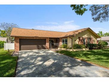 Charming single-story home featuring a brick facade, attached two-car garage, and well-maintained lawn at 2958 Macalpin N Dr, Palm Harbor, FL 34684