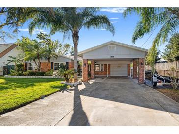 Charming single-story home with a carport and brick accents, surrounded by lush landscaping and a well-manicured lawn at 4806 Bay Crest Dr, Tampa, FL 33615