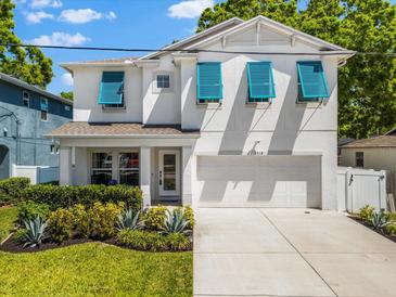 Charming two-story home featuring a two-car garage, a well-manicured lawn, and stylish blue window shutters at 6318 S Harold Ave, Tampa, FL 33616