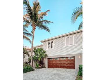 Two-story home with a paver driveway, garage, palm trees, and light gray siding at 7551 141St St, Seminole, FL 33776