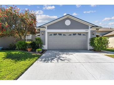 Charming home featuring a gray two-car garage, nicely landscaped yard, and a concrete driveway at 31820 Blythewood Way, Wesley Chapel, FL 33543