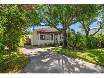 Charming single-story home featuring a red tile roof, complemented by mature trees and lush landscaping at 409 Erie Ave, Tampa, FL 33606