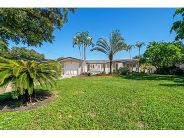 Charming single story home with a well-manicured lawn and several palm trees in the front yard at 1163 60Th S Ave, St Petersburg, FL 33705