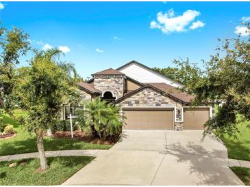 Stunning two-story home featuring stone accents and a spacious three-car garage at 5324 Moon Shell Dr, Apollo Beach, FL 33572