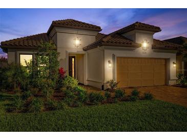 Elegant home featuring a tile roof, manicured landscaping, and a well-lit two-car garage at dusk at 4314 Graticola Rd, Wesley Chapel, FL 33543