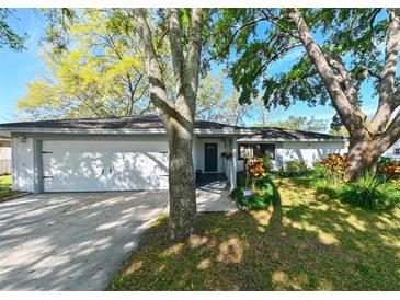 Charming single-story home featuring an attached two-car garage and beautifully landscaped front yard with mature trees at 4915 Churchill Pl, Land O Lakes, FL 34639