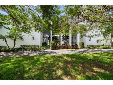 Beautiful white condominium building exterior with tropical landscaping and a manicured lawn at 50 Harbor View Ln # 21, Belleair Bluffs, FL 33770