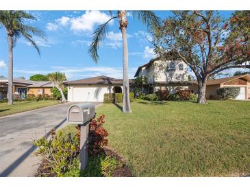 Inviting two-story home with lush lawn, mature trees, and a welcoming mailbox at 5938 Oakhurst Dr, Seminole, FL 33772