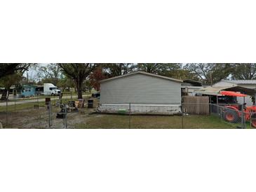 An exterior view of a mobile home and surrounding yard, with mature trees providing shade at 9907 Connecticut St, Gibsonton, FL 33534