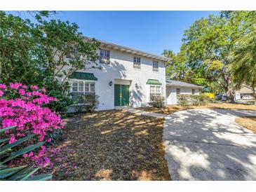 Charming two-story home features a white brick exterior, green front door, and beautiful landscaping at 13982 Whisperwood Dr, Clearwater, FL 33762