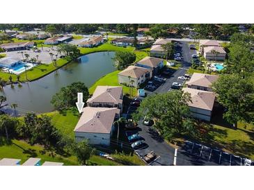 Aerial view of a condo community with a pond, mature trees, parking, and a community pool at 5026 Water Oak Dr # 220, Bradenton, FL 34207