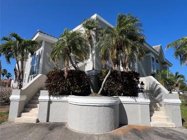 Stunning light grey home with white trim, landscaped gardens, and tropical palm trees under a clear blue sky at 816 Ponce De Leon Dr, Tierra Verde, FL 33715