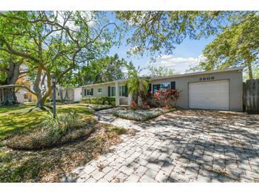 Charming single-story home with a well-manicured front yard, brick paver driveway, and mature trees at 3609 S Omar Ave, Tampa, FL 33629