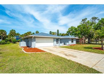 Charming single-story home featuring a two-car garage, well-maintained lawn, and tropical landscaping at 5471 Nimitz Rd, New Port Richey, FL 34652