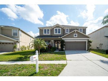 Two-story home features a well-manicured lawn, covered front porch, and attached two-car garage at 7653 Stoney Hill Dr, Wesley Chapel, FL 33545