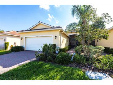 Inviting home featuring lush landscaping, a two-car garage, and a beautiful red brick driveway at 16106 Amethyst Key Dr, Wimauma, FL 33598